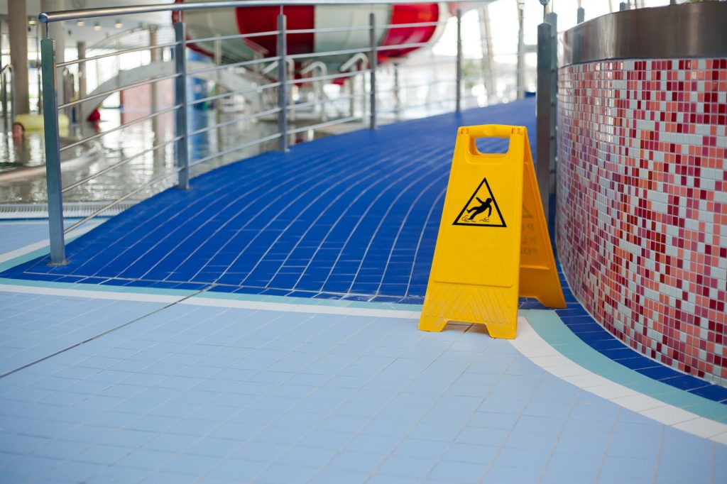 Warnung vor rutschigem Boden in gefliestem Schwimmbad