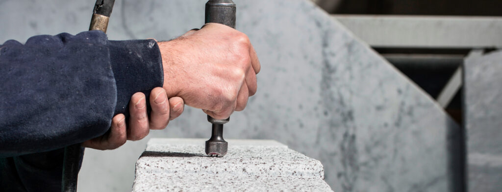 Ein Arbeiter bearbeitet Naturstein (italienischen Marmor)